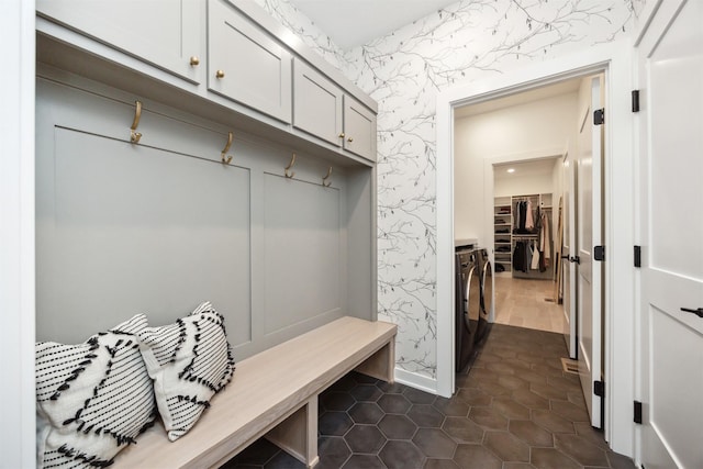 mudroom featuring dark tile patterned floors, wallpapered walls, and washing machine and clothes dryer