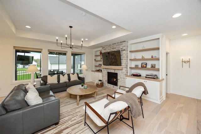 living room with a raised ceiling, baseboards, light wood finished floors, an inviting chandelier, and recessed lighting