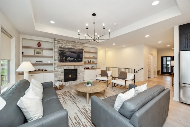 living room with recessed lighting, plenty of natural light, a raised ceiling, and light wood-style floors