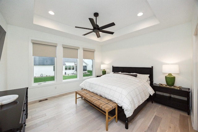 bedroom with visible vents, a raised ceiling, and light wood-style floors
