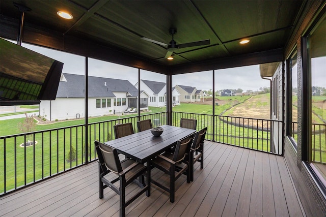 sunroom featuring a residential view, a ceiling fan, and outdoor dining space