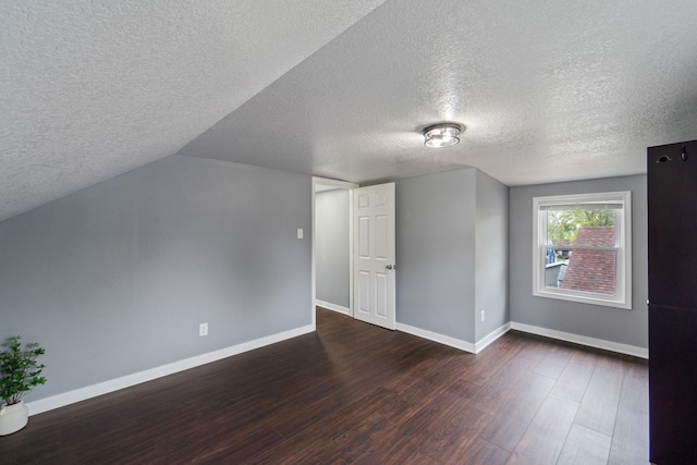 bonus room featuring dark wood-style flooring, a textured ceiling, and baseboards