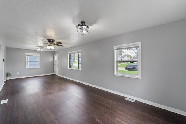 unfurnished living room with a ceiling fan, a textured ceiling, visible vents, dark wood finished floors, and baseboards