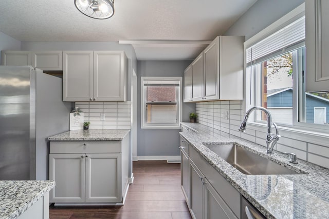 kitchen with a sink, freestanding refrigerator, gray cabinetry, and a healthy amount of sunlight