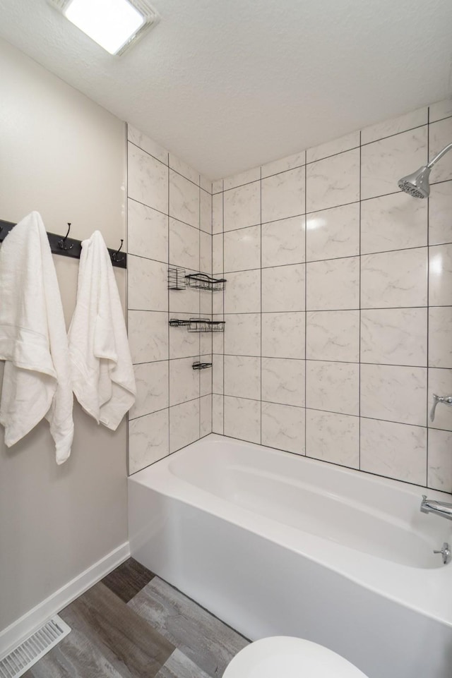 bathroom featuring shower / bath combination, baseboards, wood finished floors, and visible vents