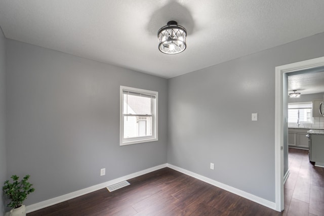 spare room with visible vents, baseboards, dark wood-type flooring, and a chandelier