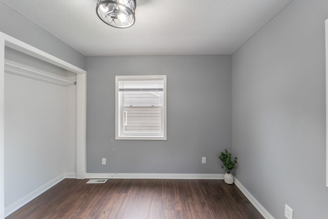 unfurnished bedroom with visible vents, dark wood finished floors, and baseboards