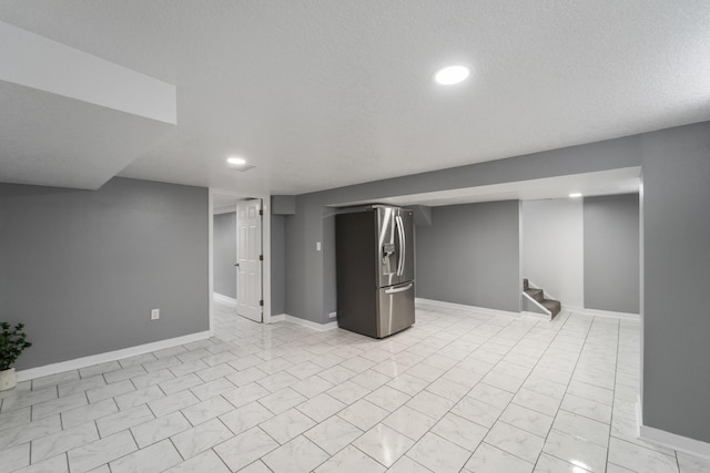 finished below grade area featuring recessed lighting, baseboards, and stainless steel fridge with ice dispenser
