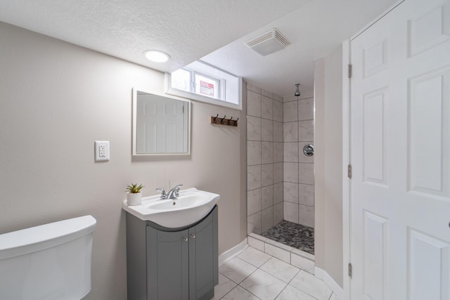 full bath featuring a tile shower, vanity, toilet, baseboards, and visible vents