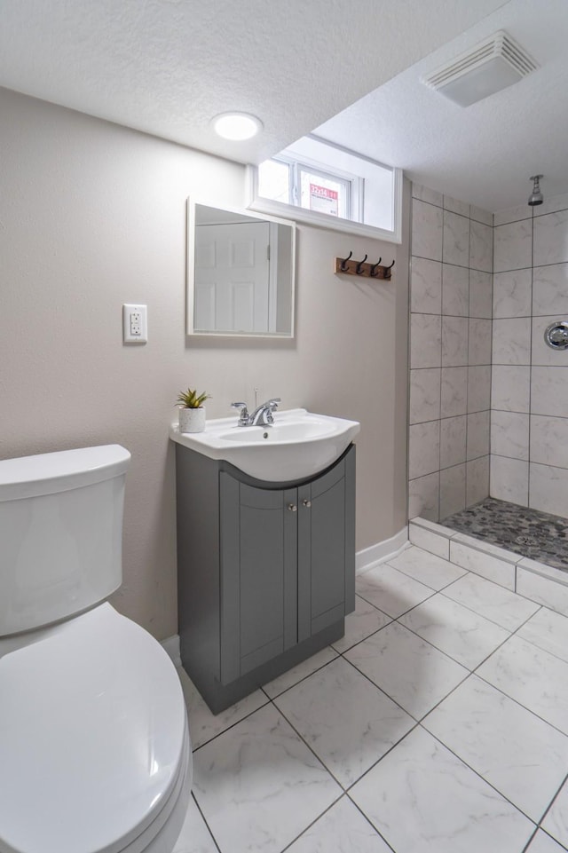 bathroom featuring a textured ceiling, visible vents, a tile shower, toilet, and marble finish floor