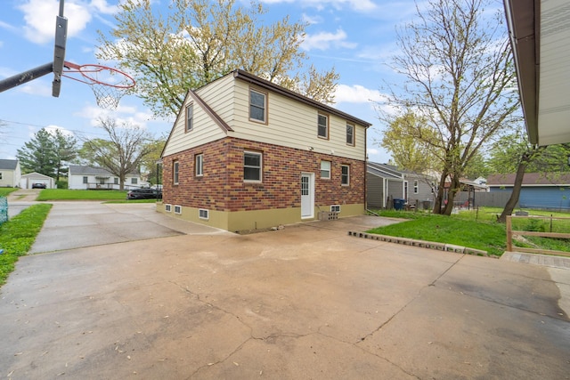 back of house featuring a yard, brick siding, fence, and concrete driveway
