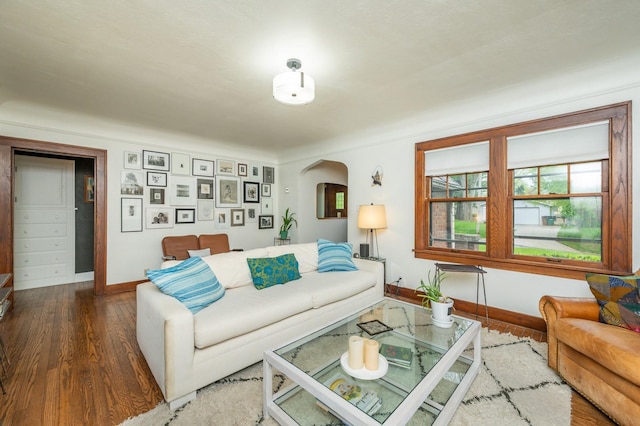 living room featuring arched walkways, baseboards, and wood finished floors
