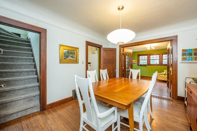 dining space featuring baseboards, wood finished floors, and stairway