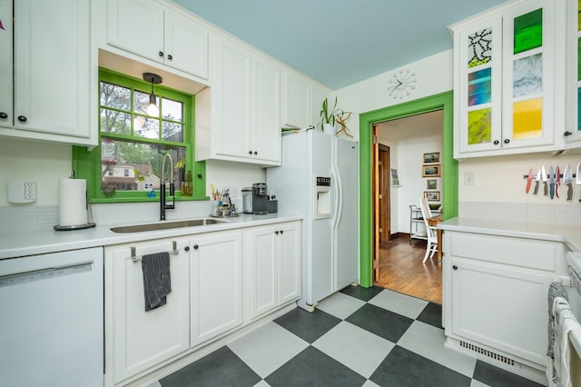 kitchen featuring a sink, dark floors, white appliances, and light countertops