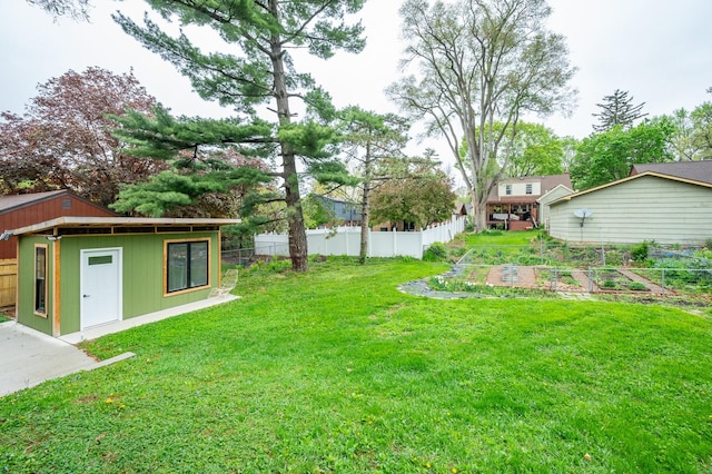 view of yard with fence, a garden, and an outbuilding
