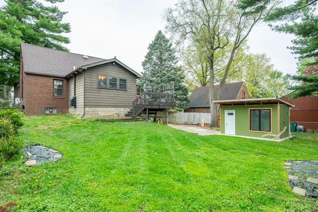 rear view of house with stairs, a lawn, fence, and a deck