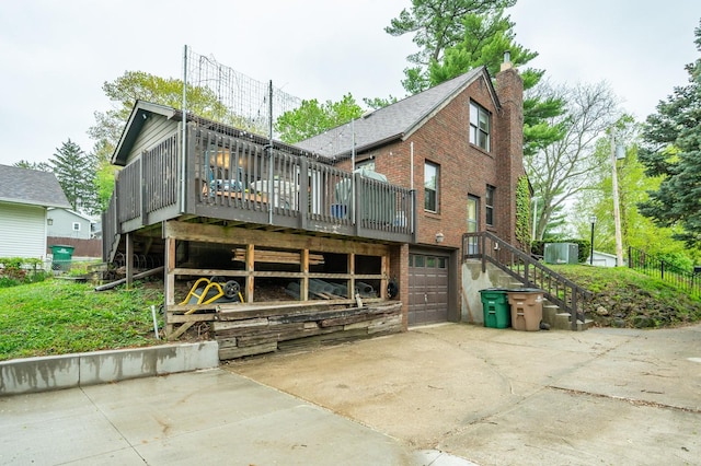 back of house featuring a garage, a deck, brick siding, concrete driveway, and stairway