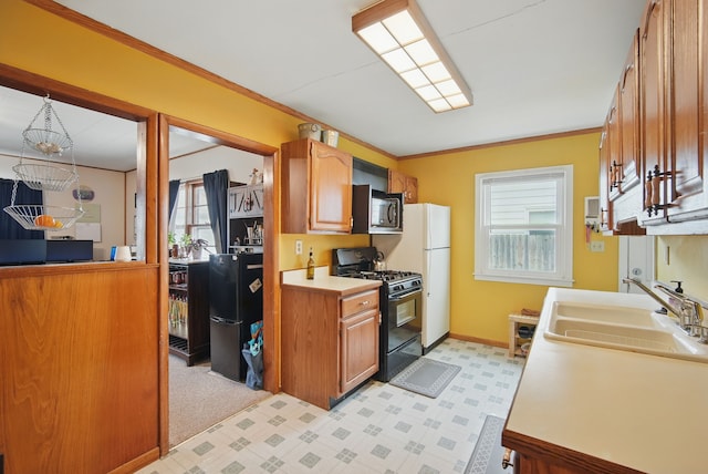 4131 Cornell St, Des Moines, IA 50313 - kitchen with ornamental molding, light floors, light countertops, a sink, and black appliances