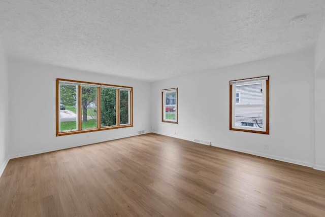 4038 57th St, Des Moines, IA 50310 - empty room featuring a textured ceiling, baseboards, wood finished floors, and visible vents