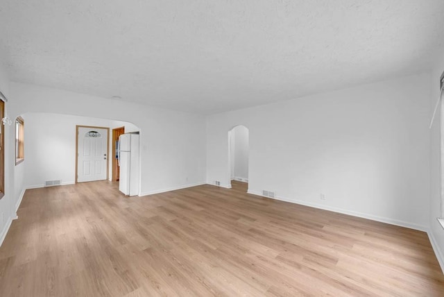 4038 57th St, Des Moines, IA 50310 - unfurnished living room featuring arched walkways, light wood-type flooring, a textured ceiling, and visible vents