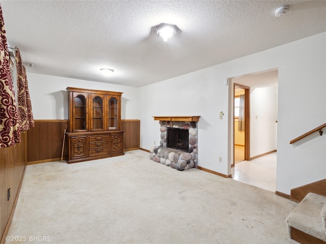 4508 SE 3rd St, Des Moines, IA 50315 - living room featuring a stone fireplace, a textured ceiling, carpet floors, and a wainscoted wall