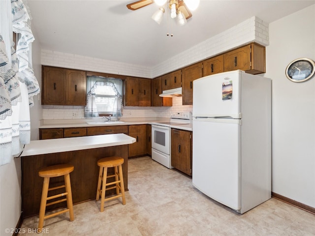 4508 SE 3rd St, Des Moines, IA 50315 - kitchen featuring a sink, white appliances, light countertops, a peninsula, and under cabinet range hood