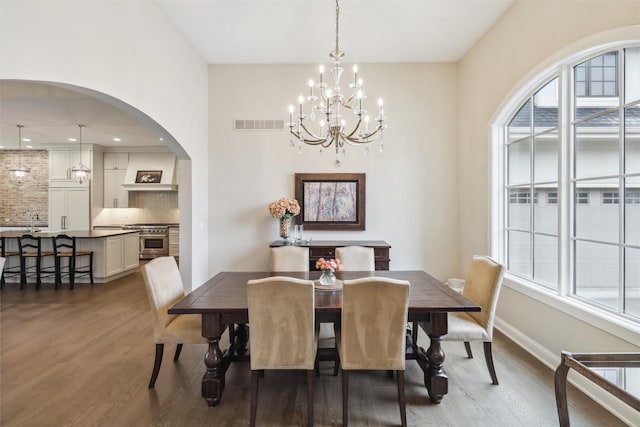 73 Myles Ct, Waukee, IA 50263 - dining room with wood finished floors, visible vents, arched walkways, a notable chandelier, and baseboards