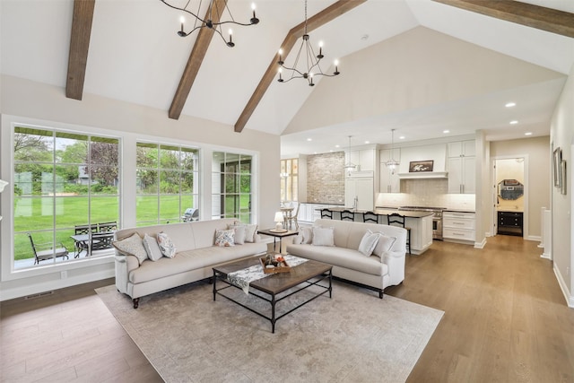 living area featuring a wealth of natural light, light wood-style flooring, a chandelier, and high vaulted ceiling