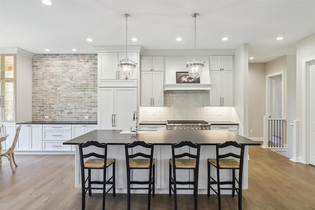 73 Myles Ct, Waukee, IA 50263 - kitchen featuring backsplash, a kitchen bar, dark countertops, and a center island with sink