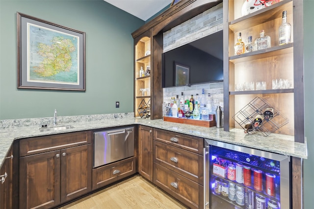 bar featuring a sink, light wood-style floors, dishwasher, beverage cooler, and a bar