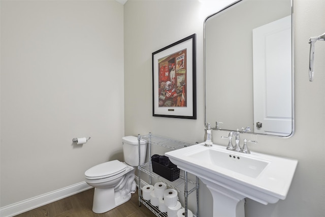 bathroom with baseboards, wood finished floors, and toilet