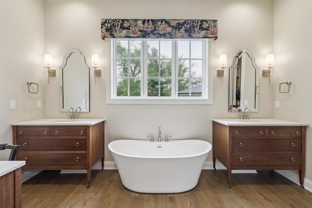 73 Myles Ct, Waukee, IA 50263 - full bathroom featuring a soaking tub, wood finished floors, two vanities, and a sink