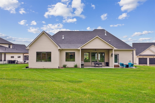 rear view of property featuring a lawn, ceiling fan, a shingled roof, and a patio area