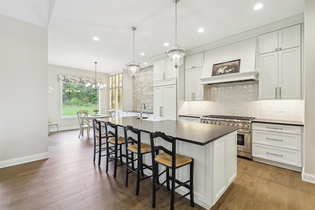 73 Myles Ct, Waukee, IA 50263 - kitchen featuring a kitchen island with sink, dark wood-type flooring, backsplash, double oven range, and custom range hood