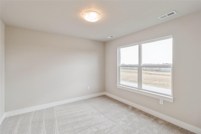 unfurnished room with baseboards, visible vents, and light carpet