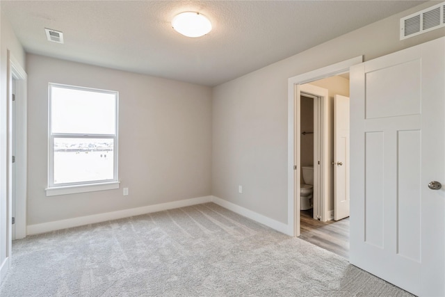 spare room with visible vents, baseboards, and light colored carpet