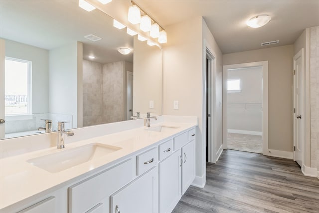 bathroom with a sink, a wealth of natural light, wood finished floors, and visible vents