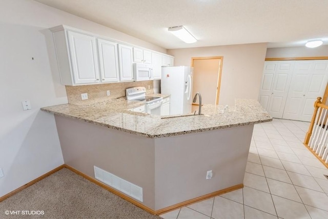 7422 SE 23rd St Unit 6, Des Moines, IA 50320 - kitchen featuring light stone countertops, white appliances, a peninsula, tasteful backsplash, and visible vents