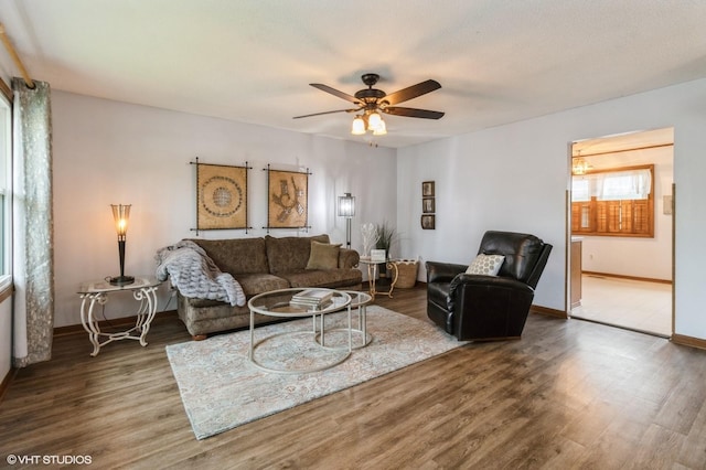living room featuring baseboards, a ceiling fan, and wood finished floors