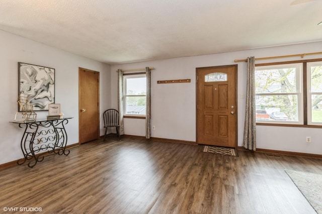 foyer entrance featuring baseboards, wood finished floors, and visible vents