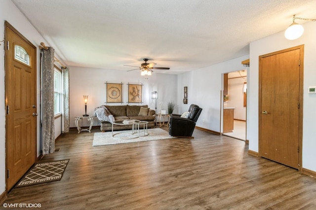 living area featuring a ceiling fan, baseboards, and wood finished floors