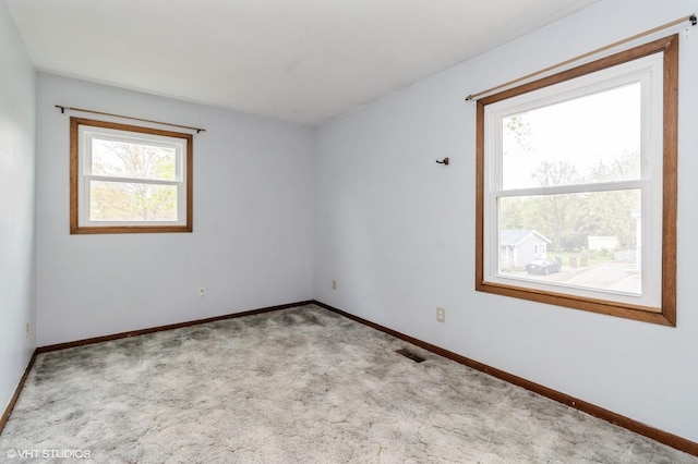 empty room featuring carpet flooring, baseboards, and visible vents