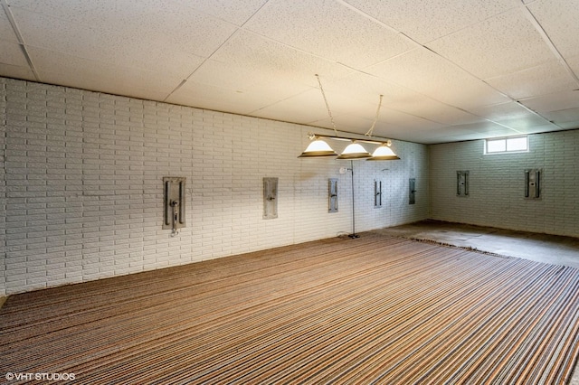 interior space featuring a paneled ceiling and brick wall