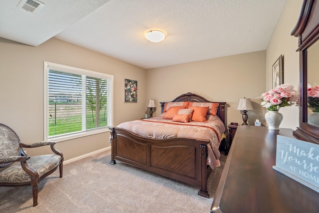 bedroom with baseboards, light carpet, a textured ceiling, and visible vents