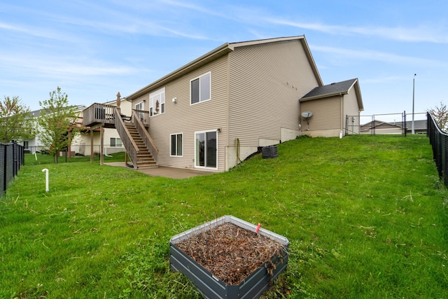 rear view of house featuring a yard, a deck, a fenced backyard, and stairs