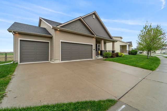 craftsman-style house with concrete driveway, an attached garage, fence, and a front lawn