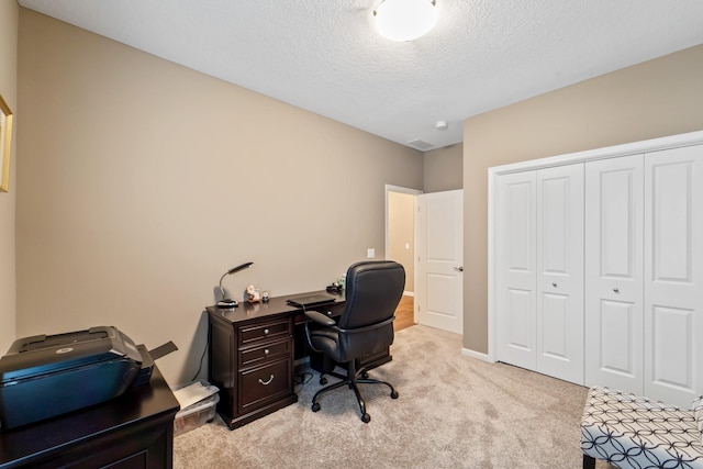 office space with a textured ceiling, visible vents, light carpet, and baseboards