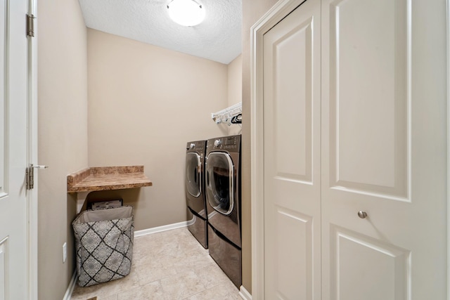 laundry area with laundry area, a textured ceiling, baseboards, tile patterned floors, and separate washer and dryer