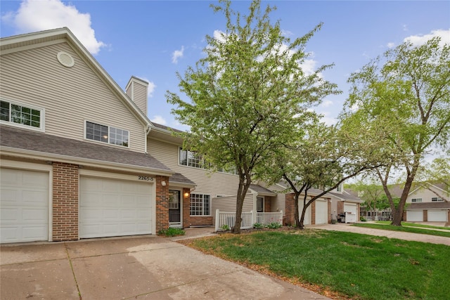 multi unit property featuring a garage, a chimney, a front yard, and brick siding