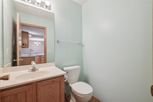 half bath with toilet, baseboards, and vanity